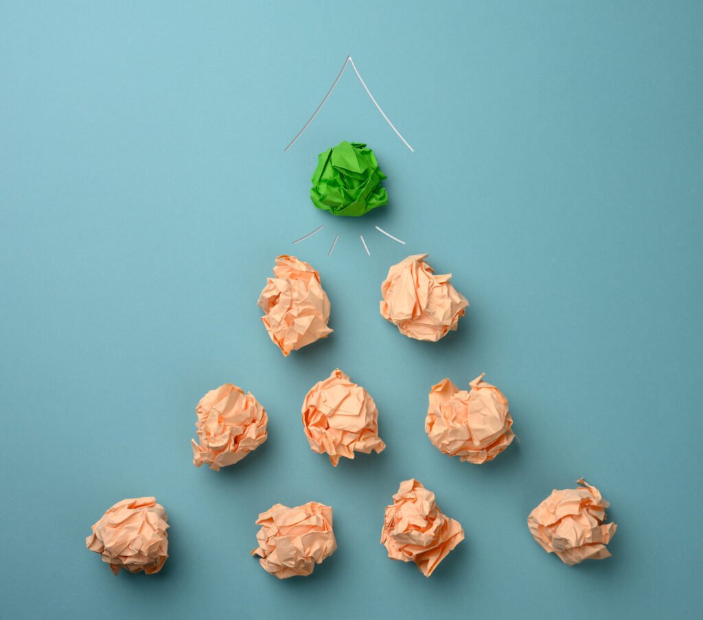 Ilustração de growth em estágio inicial com várias bolas de papel amassado bege e uma bola verde no topo sob o desenho de um foguete, representando testes, erros e crescimento em startups